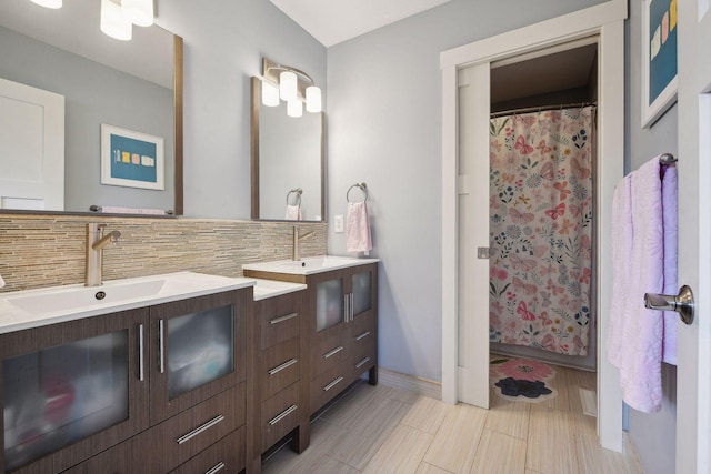 full bathroom featuring a shower with shower curtain, baseboards, backsplash, and vanity