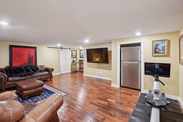 living area with recessed lighting, visible vents, a barn door, baseboards, and hardwood / wood-style flooring