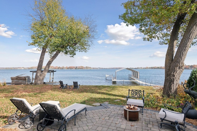 view of patio / terrace featuring an outdoor fire pit, a boat dock, and a water view