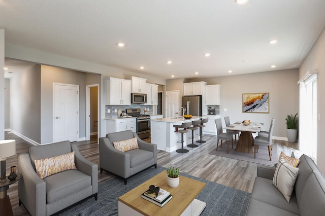 living room featuring baseboards, recessed lighting, and light wood-style floors