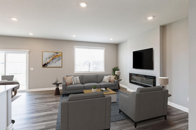 living area with a glass covered fireplace, recessed lighting, baseboards, and wood finished floors