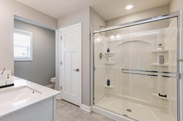 bathroom with toilet, a shower stall, baseboards, and vanity