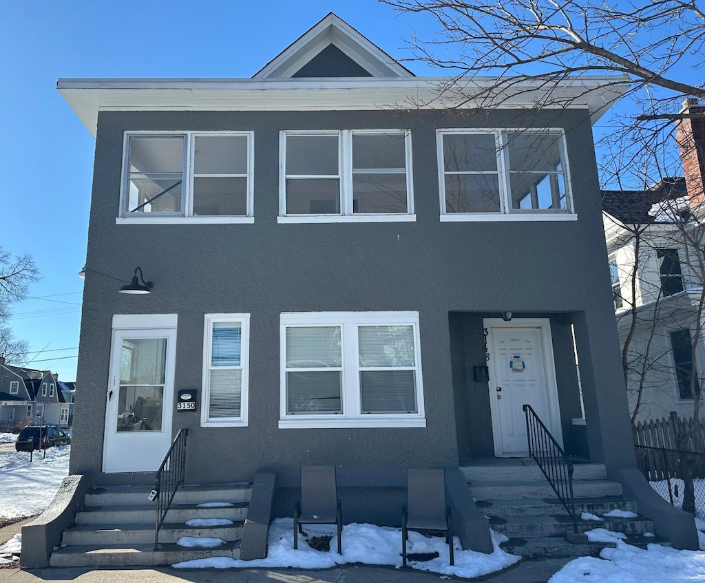 multi unit property featuring entry steps, fence, and stucco siding