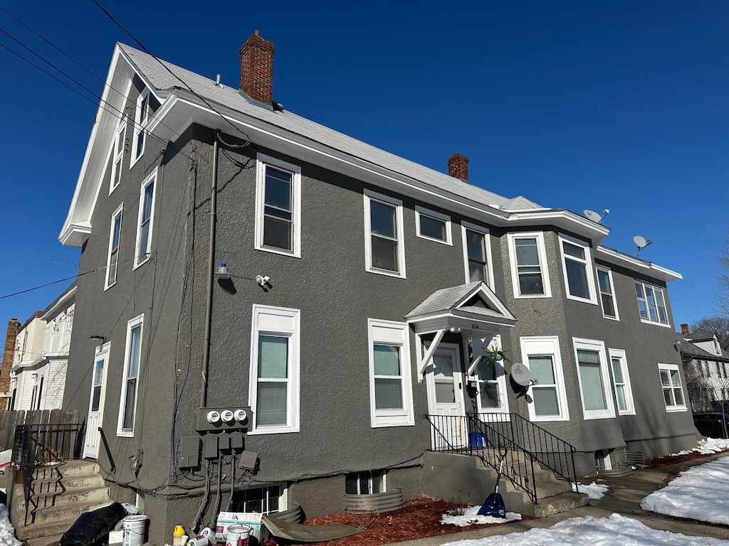 view of front of property featuring a chimney and stucco siding