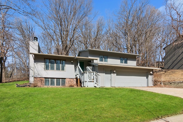 tri-level home with driveway, a front lawn, a garage, brick siding, and a chimney