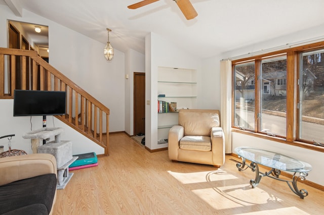 living area with baseboards, stairway, vaulted ceiling, wood finished floors, and a ceiling fan