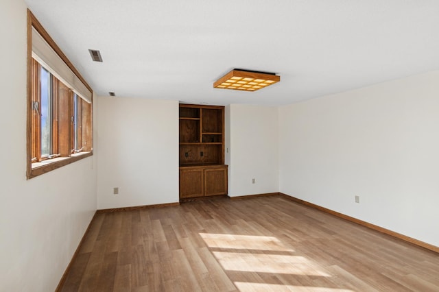 unfurnished room featuring visible vents, baseboards, and light wood finished floors