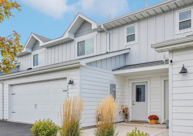 multi unit property featuring roof with shingles, board and batten siding, and an attached garage