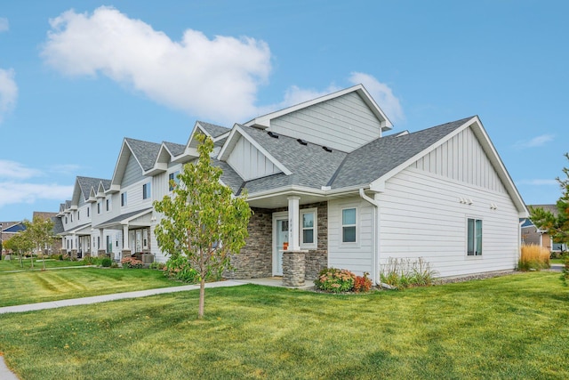 view of front of house featuring central air condition unit, a shingled roof, board and batten siding, stone siding, and a front lawn