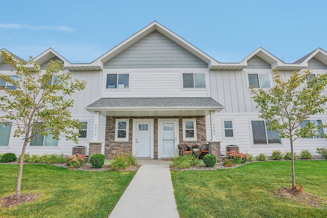 multi unit property with stone siding, central AC, a front lawn, and board and batten siding