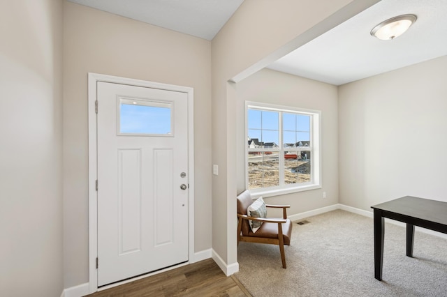 foyer entrance featuring visible vents, baseboards, and wood finished floors