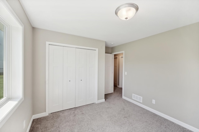 unfurnished bedroom with carpet floors, a closet, visible vents, and baseboards