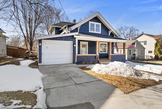 bungalow-style home with board and batten siding, fence, a porch, driveway, and an attached garage