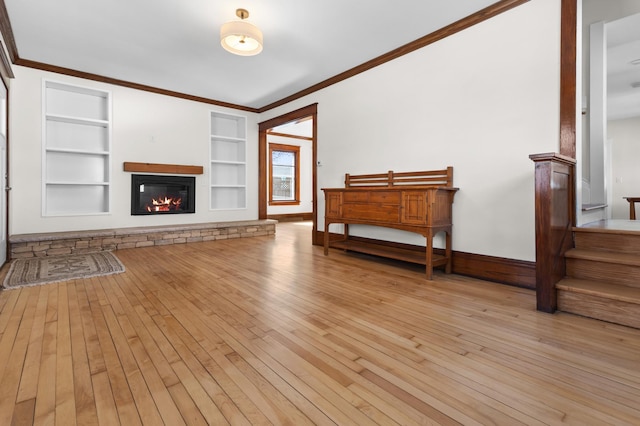 living room with a glass covered fireplace, light wood-style flooring, crown molding, and baseboards