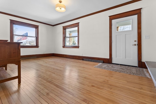 foyer entrance featuring crown molding, light wood-style floors, and baseboards