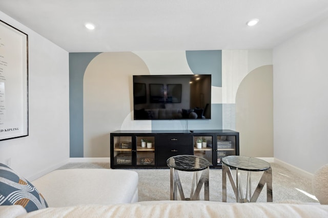 carpeted living room featuring baseboards, arched walkways, and recessed lighting