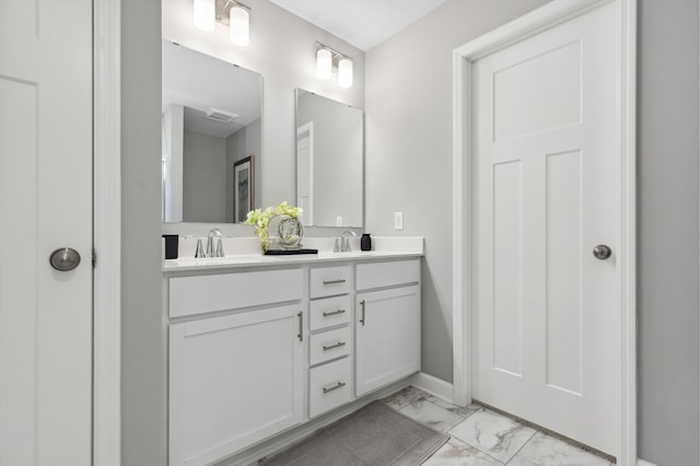 full bath with marble finish floor, double vanity, and a sink