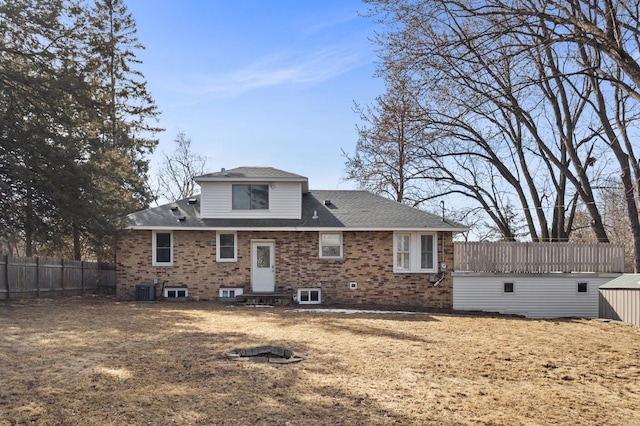 back of property with cooling unit, brick siding, roof with shingles, and fence