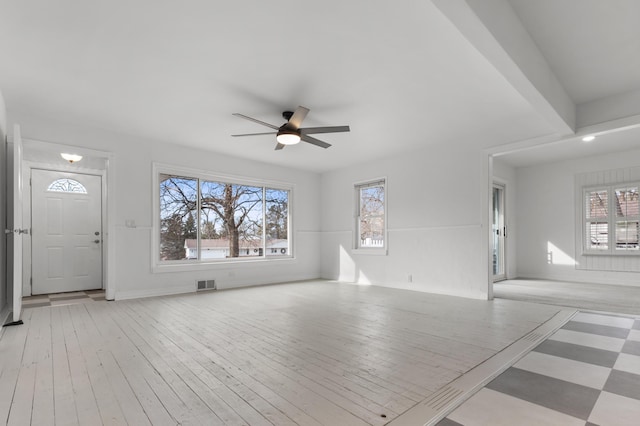 unfurnished living room with visible vents, a healthy amount of sunlight, a ceiling fan, and hardwood / wood-style flooring