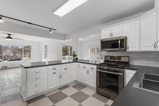 kitchen featuring white cabinetry, dark countertops, light floors, and stainless steel appliances