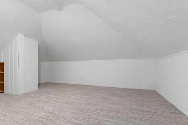 bonus room with lofted ceiling, carpet flooring, and a textured ceiling