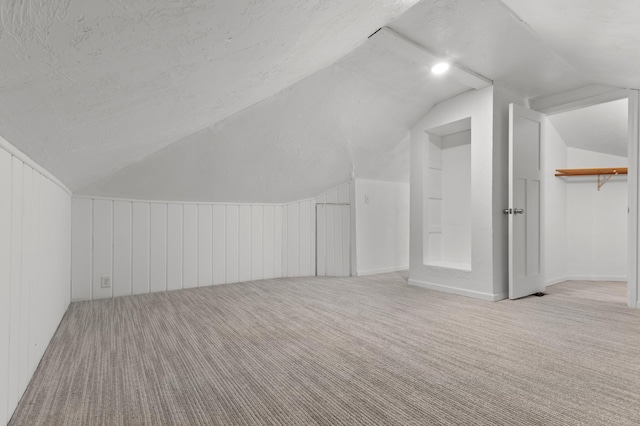 additional living space with lofted ceiling, carpet, and a textured ceiling