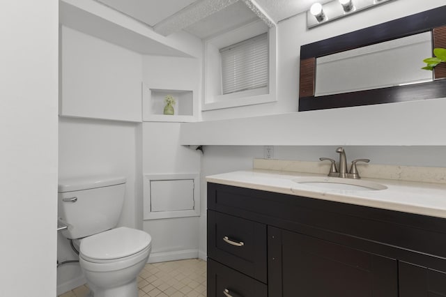 bathroom featuring vanity, toilet, baseboards, and tile patterned flooring