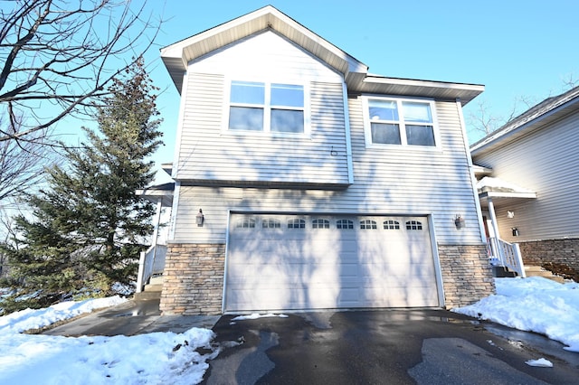 view of front of property with aphalt driveway, a garage, and stone siding