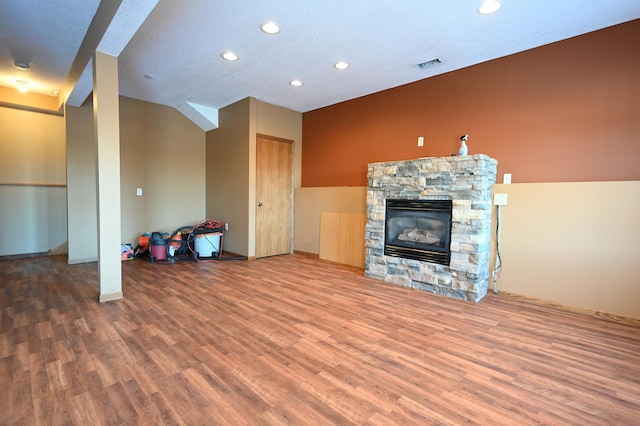 unfurnished living room featuring a stone fireplace, recessed lighting, wood finished floors, and visible vents