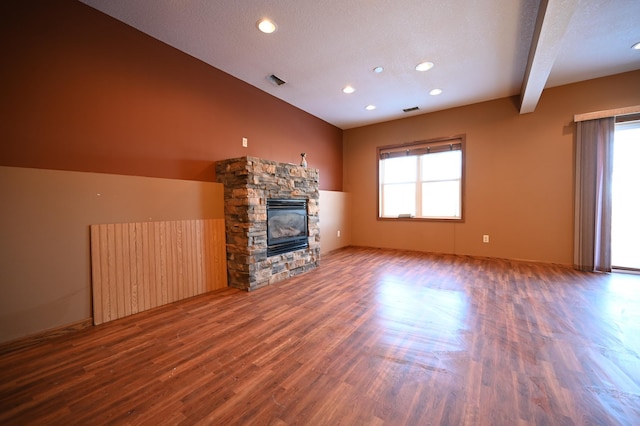 unfurnished living room with a wealth of natural light, visible vents, a fireplace, and wood finished floors