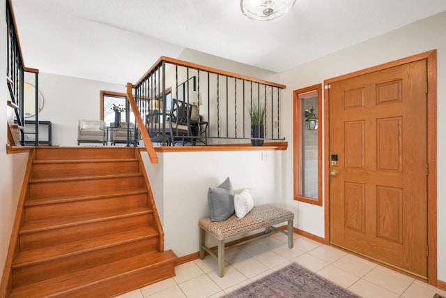 entryway featuring baseboards, stairs, and tile patterned flooring