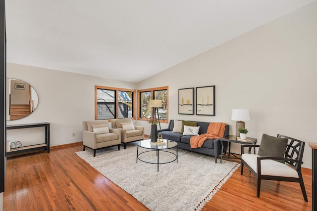 living area featuring lofted ceiling, wood finished floors, and baseboards