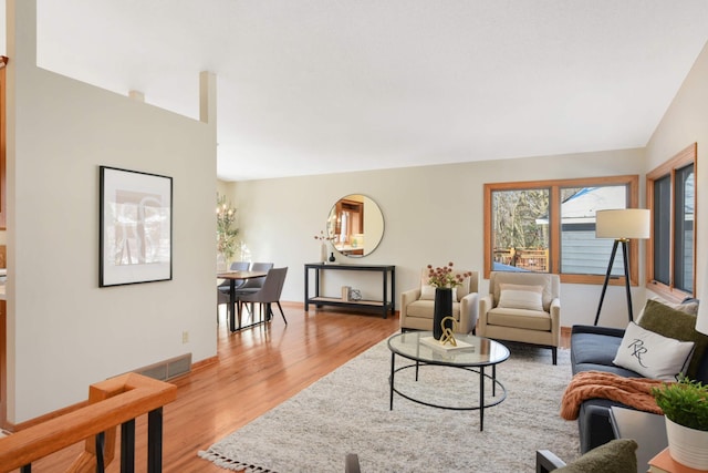 living room featuring lofted ceiling, visible vents, and light wood finished floors