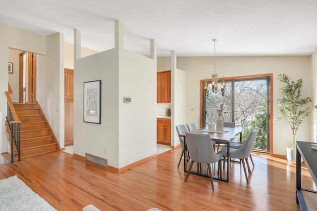 dining room featuring visible vents, lofted ceiling, stairs, and light wood finished floors