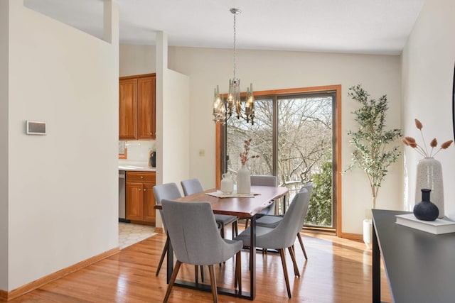 dining space featuring a notable chandelier, plenty of natural light, light wood-type flooring, and vaulted ceiling