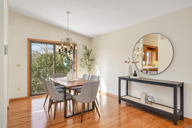 dining space featuring baseboards, lofted ceiling, an inviting chandelier, and wood finished floors