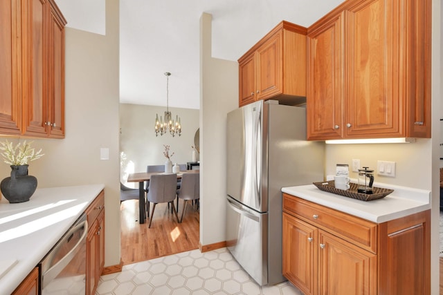 kitchen featuring pendant lighting, stainless steel appliances, brown cabinetry, light countertops, and a chandelier