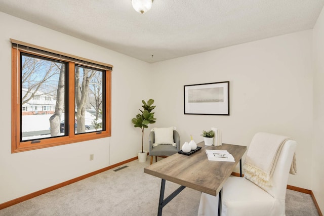 office featuring visible vents, baseboards, light colored carpet, and a textured ceiling