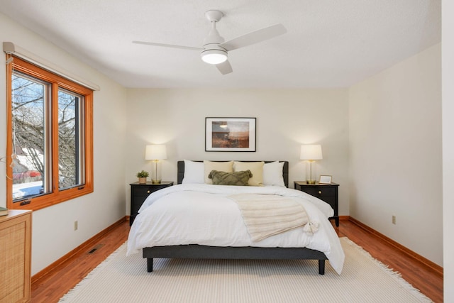 bedroom with light wood-style floors, baseboards, and ceiling fan