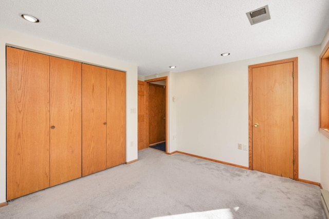 unfurnished bedroom featuring visible vents, a textured ceiling, a closet, carpet flooring, and baseboards