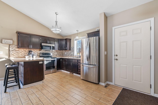 kitchen featuring light wood-style flooring, a peninsula, stainless steel appliances, and light countertops