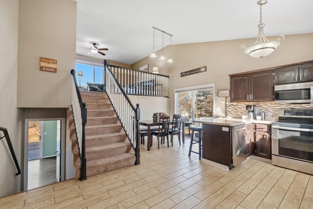 kitchen with decorative light fixtures, stainless steel appliances, dark brown cabinets, and light wood finished floors