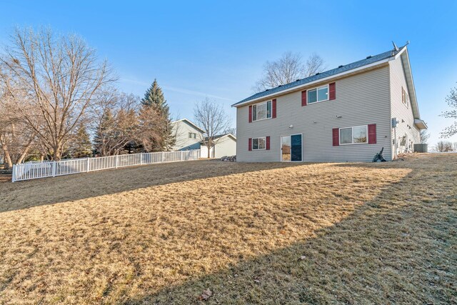 back of property featuring central air condition unit, fence, and a lawn