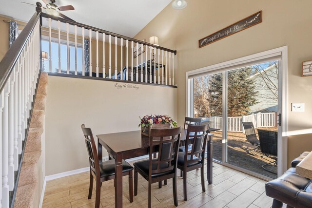 dining space with wood finished floors, baseboards, a towering ceiling, and ceiling fan