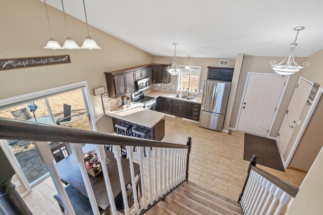 stairway featuring visible vents, baseboards, wood finished floors, and vaulted ceiling