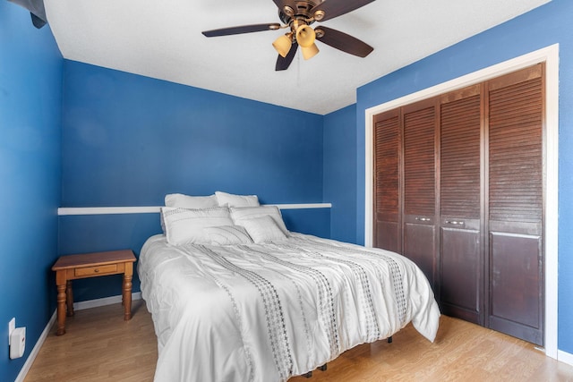 bedroom with a ceiling fan, wood finished floors, a closet, and baseboards