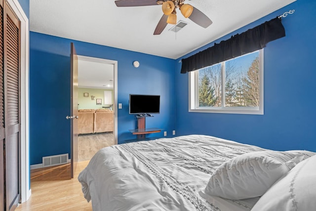 bedroom with a closet, visible vents, ceiling fan, and wood finished floors