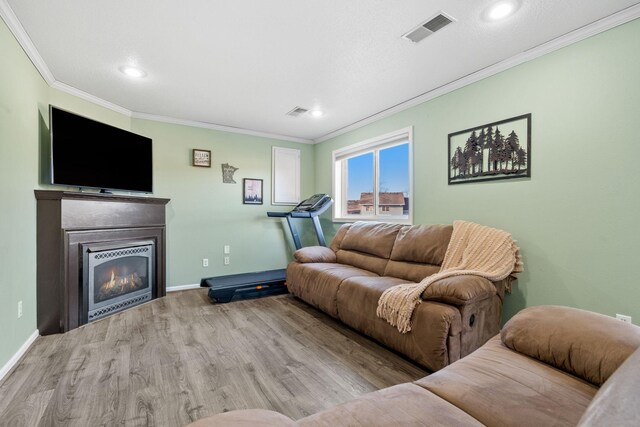 living room with baseboards, wood finished floors, visible vents, and ornamental molding