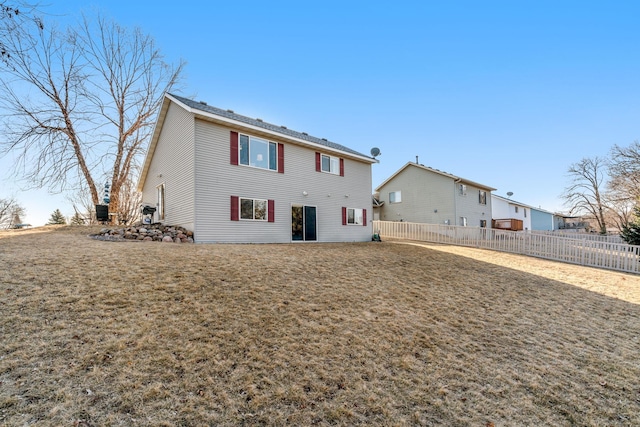 rear view of property with a lawn and fence