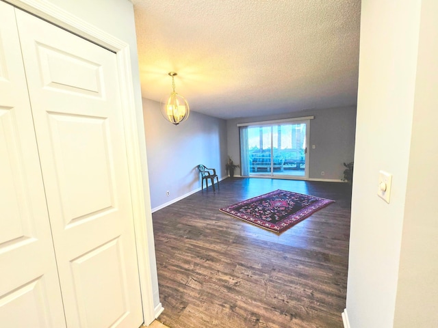 interior space with a notable chandelier, a textured ceiling, baseboards, and wood finished floors